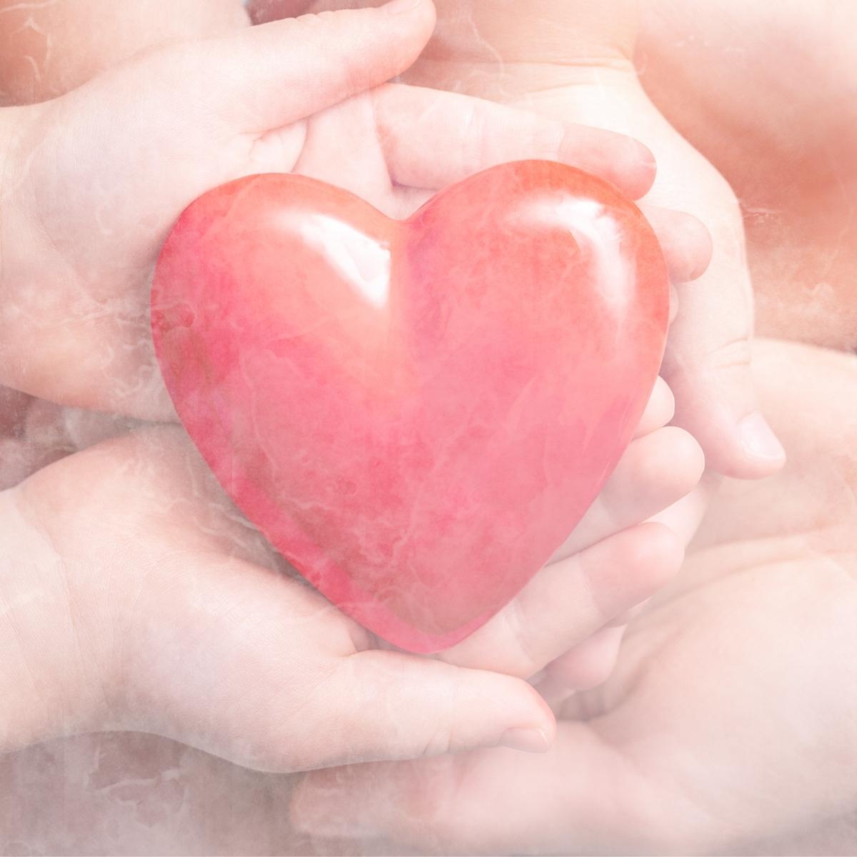 Hands of a mother and child holding a heart